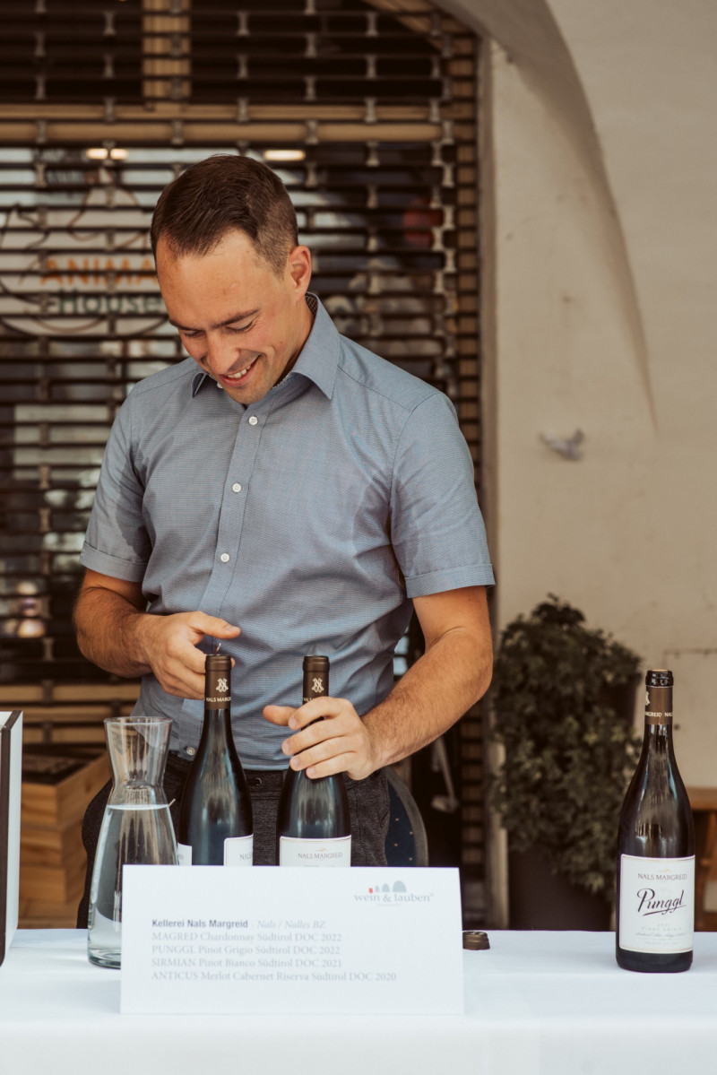 A photo of a man opening a winebottle