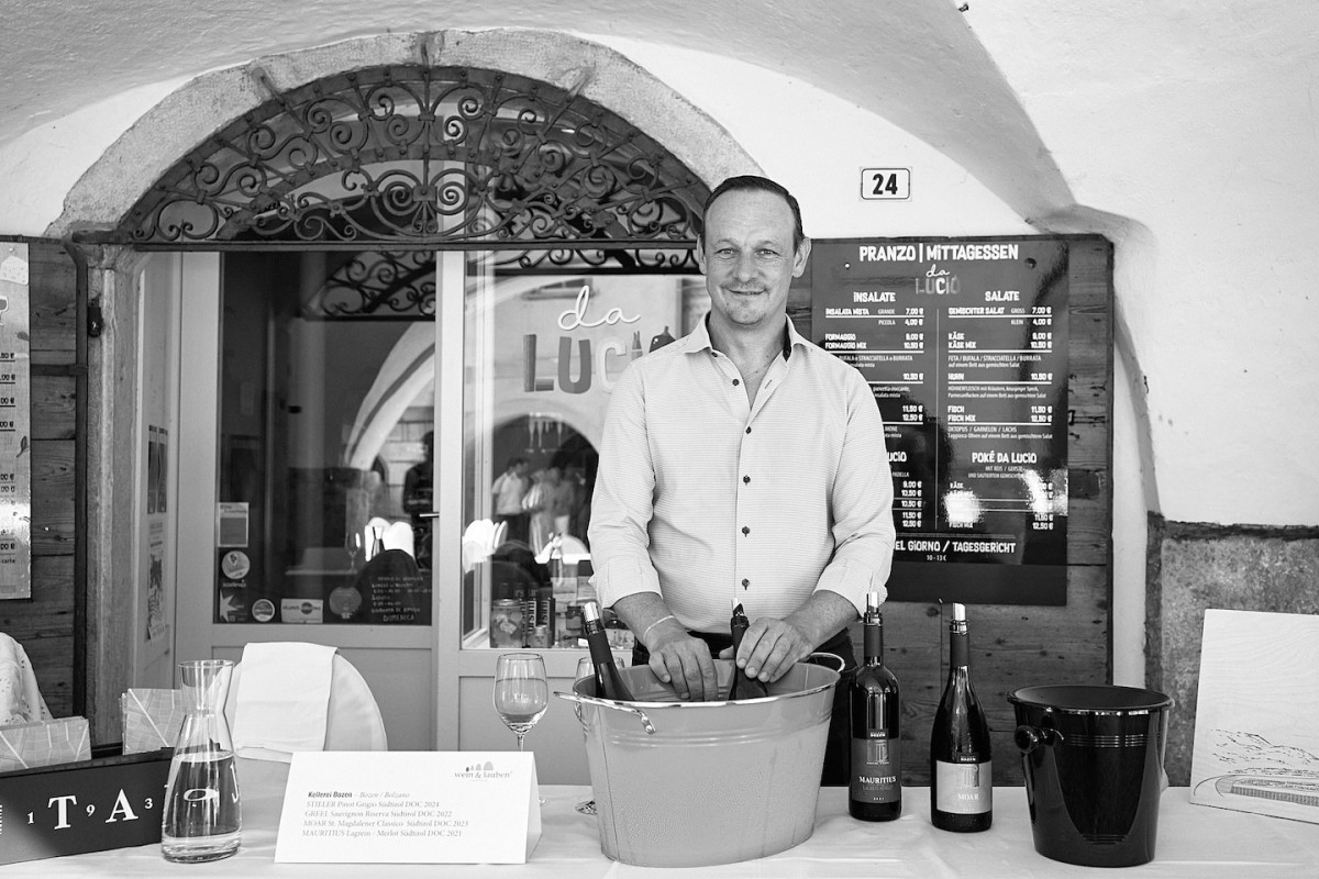 Ein Vertreter von Kellerei Bozen steht hinter einem Tisch und präsentiert Weine.