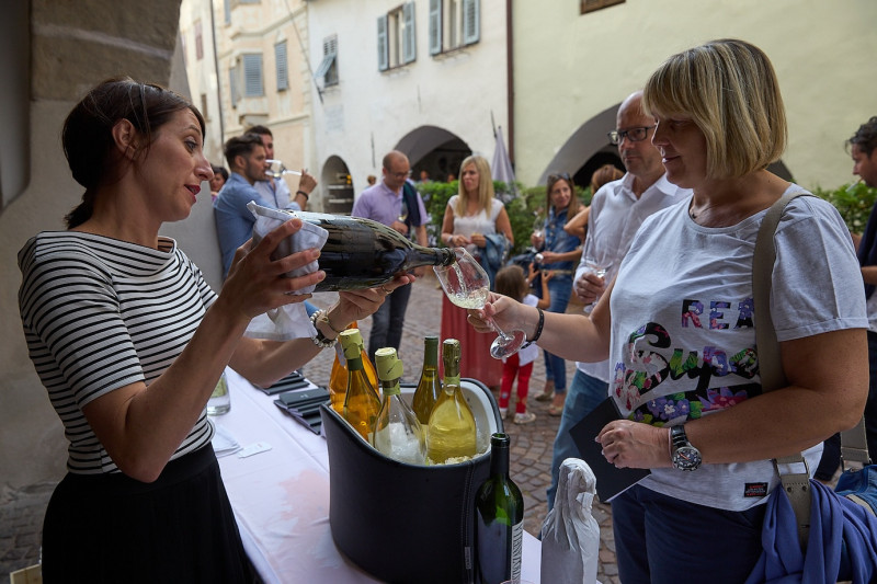 A photo of a woman pouring wine into the glass of another woman at the Wine & Arcades event
